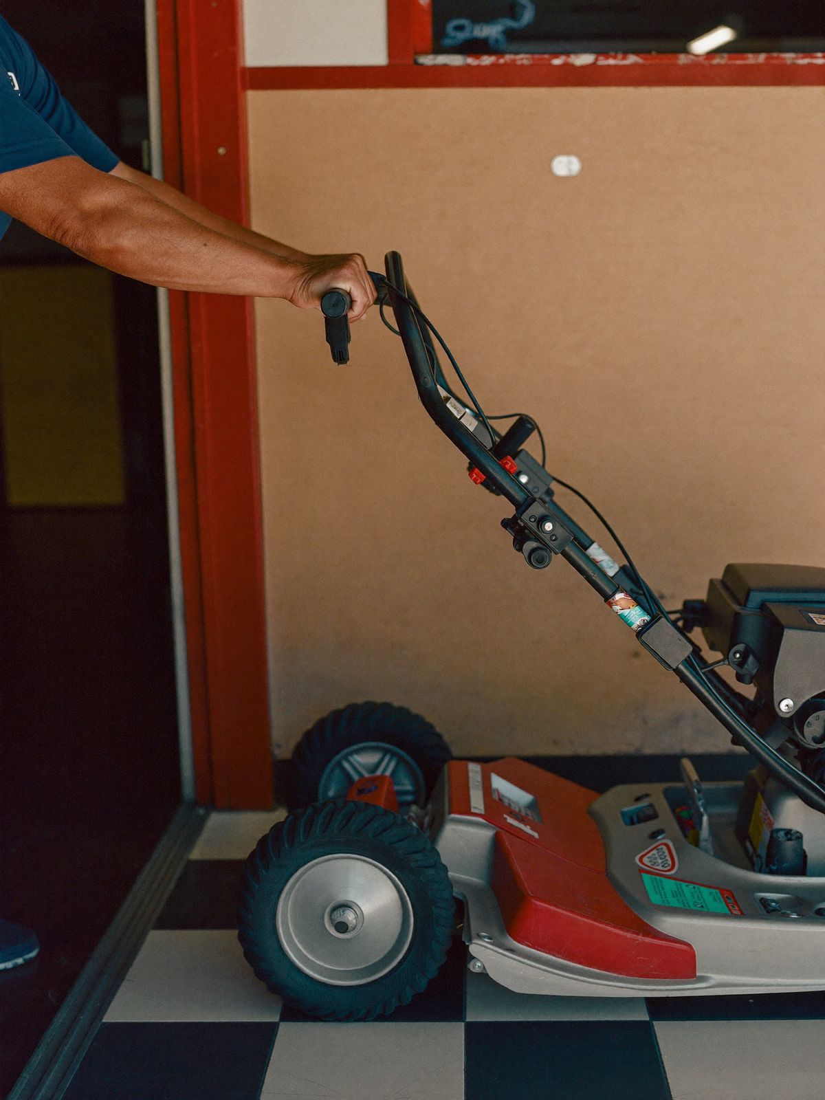 A mechanic pushing a customer's lawn mower into the Iraheta Services shop in Palmdale, CA