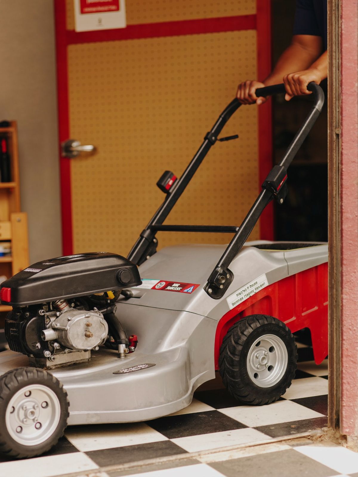 A mechanic pushing a repaired lawn mower out of the shop